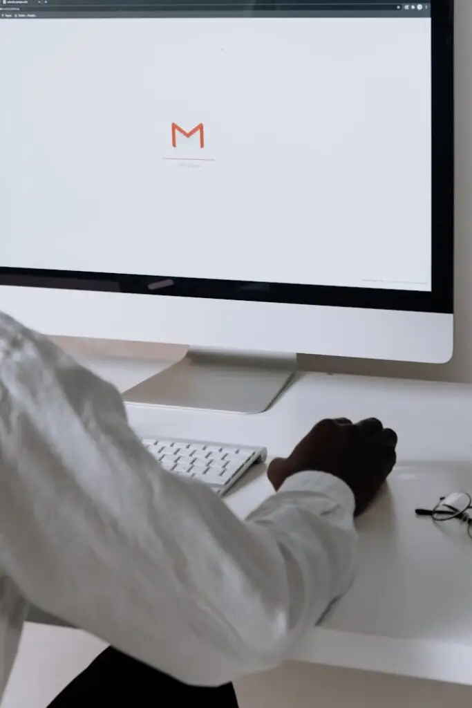 A professional in an office setting checking emails on a desktop computer with a clean workspace.